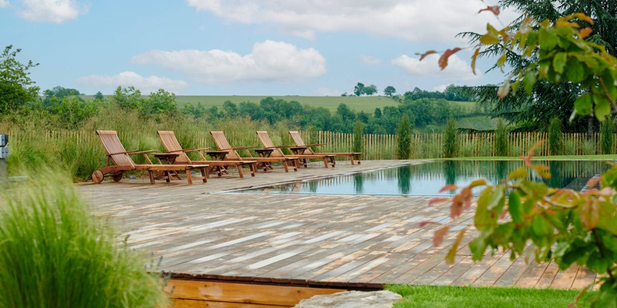 Rénovation piscine à Aurillac : donnez une nouvelle vie à votre bassin avec Catusse Piscines & Spas 7 Rénovation d'un couloir de nage aux dimensions 14,00 x 4,00 m relevé de 0,60 m et décalé de 2,00 m avec un terrasse en bois et des margelles gris clair