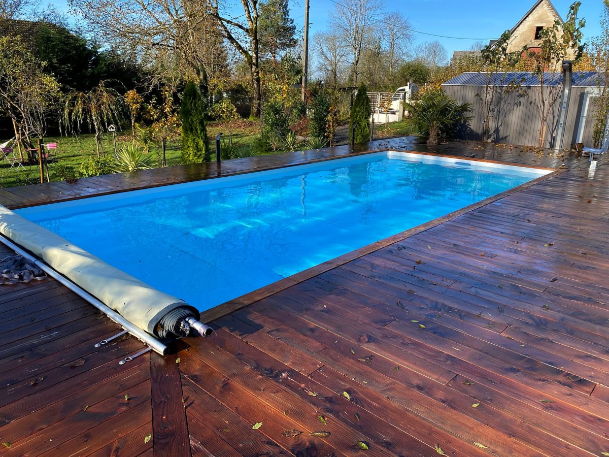 Piscine avec couverture à barre et plage en bois - Catusse Piscines & Spas