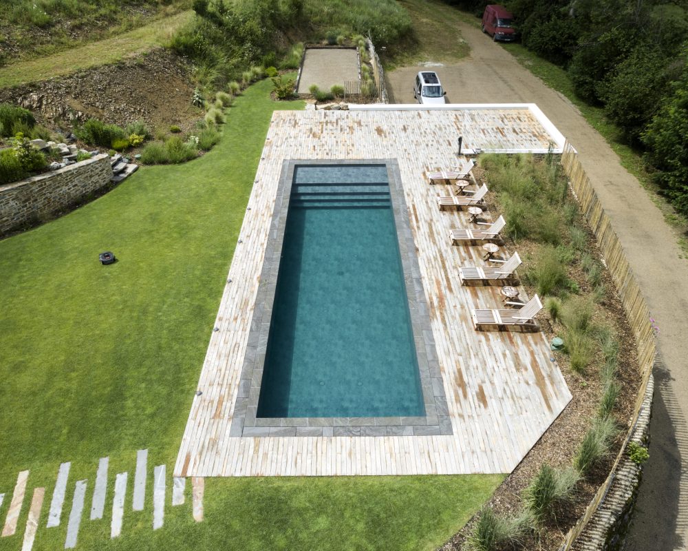 Construction de piscines avec Catusse Piscines & Spas 8 Rénovation d'un couloir de nage aux dimensions 14,00 x 4,00 m relevé de 0,60 m et décalé de 2,00 m avec un terrasse en bois et des margelles gris clair