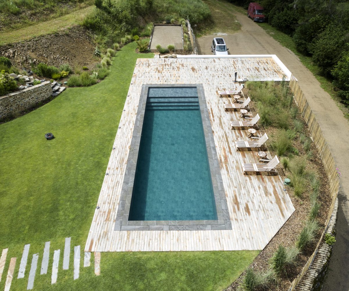Pisciniste à Figeac 5 Rénovation d'un couloir de nage aux dimensions 14,00 x 4,00 m relevé de 0,60 m et décalé de 2,00 m avec un terrasse en bois et des margelles gris clair