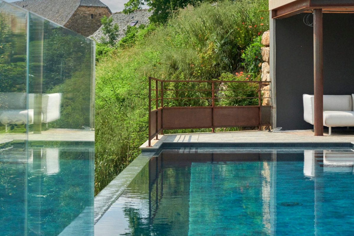 Piscine à débordement sur la largeur de 9 x 3,5 m, profondeur 1,20 à 1,80 m avec escalier d’angle et banquette volet