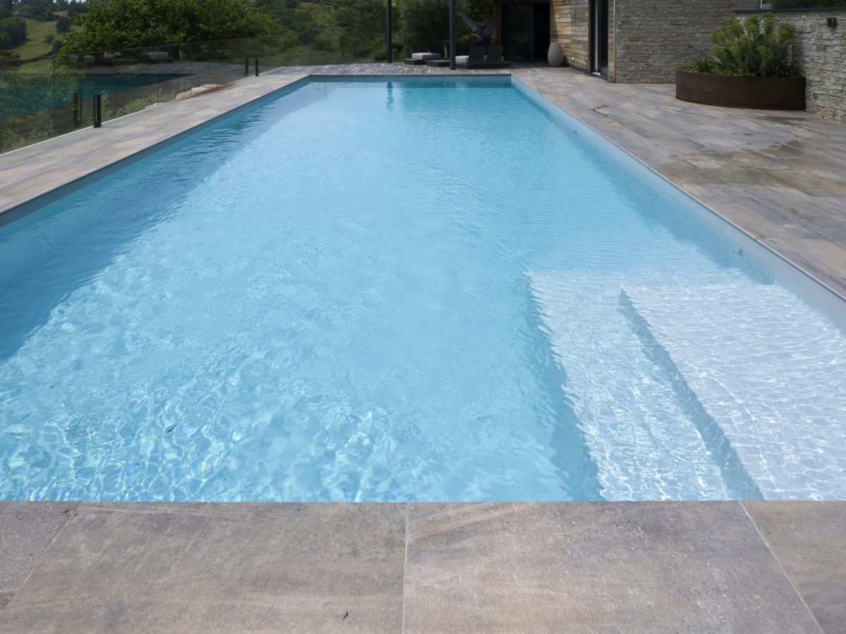 Le guide du liner piscine : options, tarifs et devis 4 Piscine rectangulaire 16x5,5m avec plage et lagon grès cérame